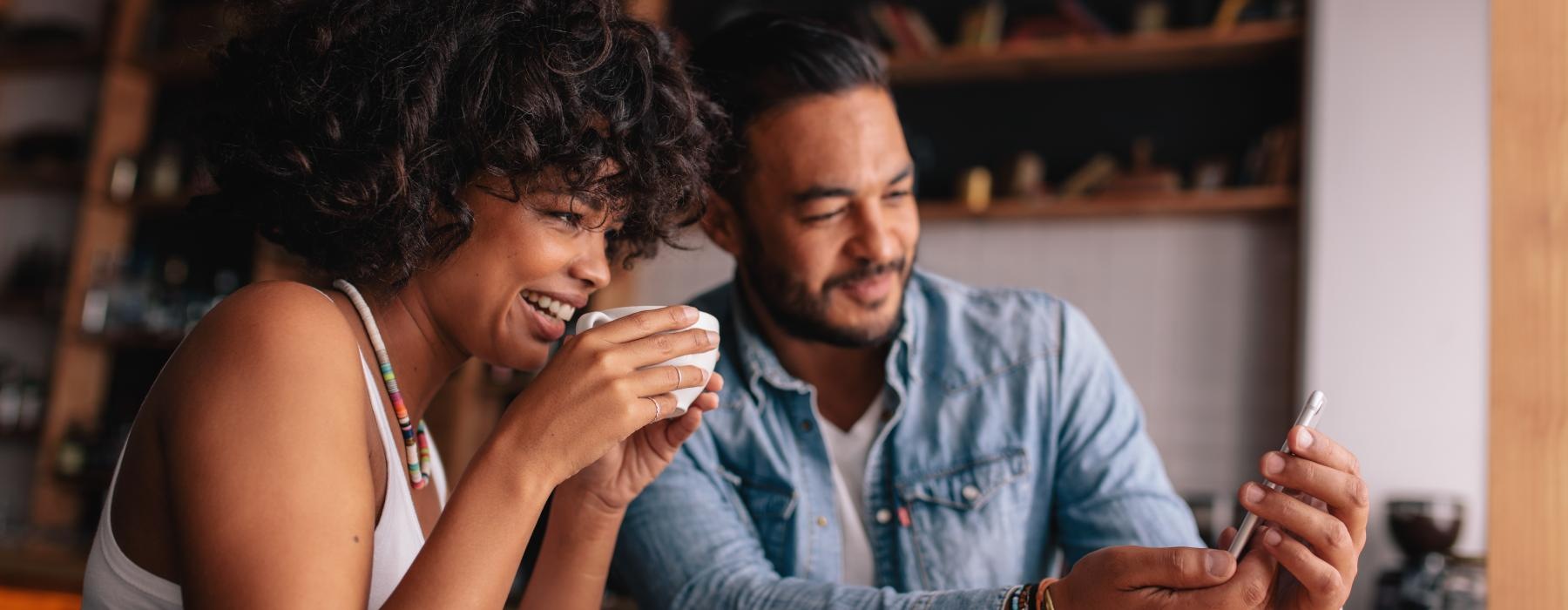 a man and woman sitting at a table and looking at a phone